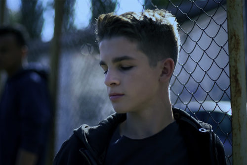 young men leaning on metal fence